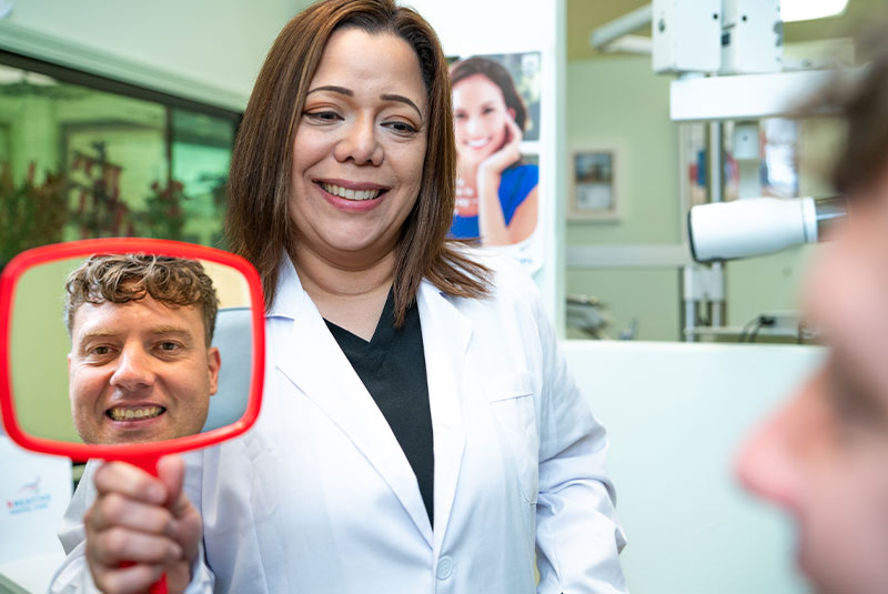 Doctor holding up mirror for Paitent to see their teeth