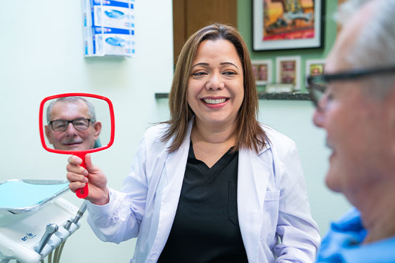 Doctor holding up a mirror for Patient to see their new smile
